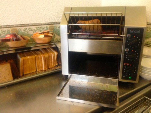 O café da manhã no Grainger era self service meio tosco mas esta torradeira me chamou a atenção. É uma esteira rolante onde você põe o pão e dali a pouco cai a torrada./ In the rough self service breakfast at the Grainger, I took notice of this toaster, a conveyor-belt where you put the bread and in a couple of minutes the toast comes out ready